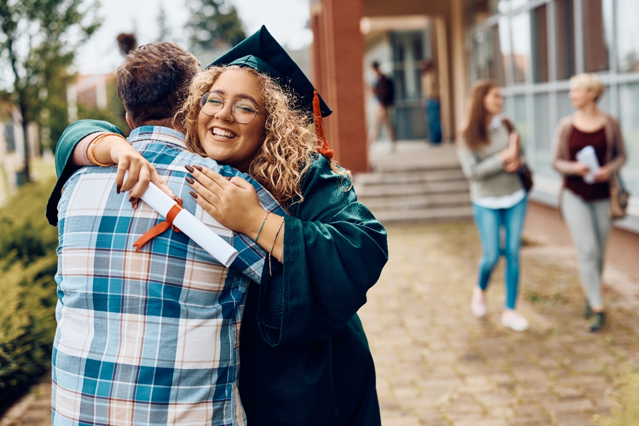 Happy student hugging her father after receiving diploma on graduation day at the university.